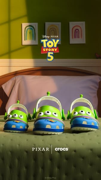 Disney Pixar Toy Story 5 x Crocs ad: three Alien clogs lined up on a bed