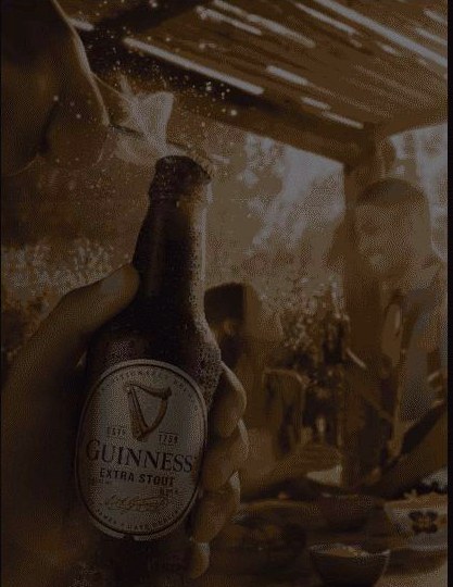 Guinness Extra Stout bottle held up outdoors